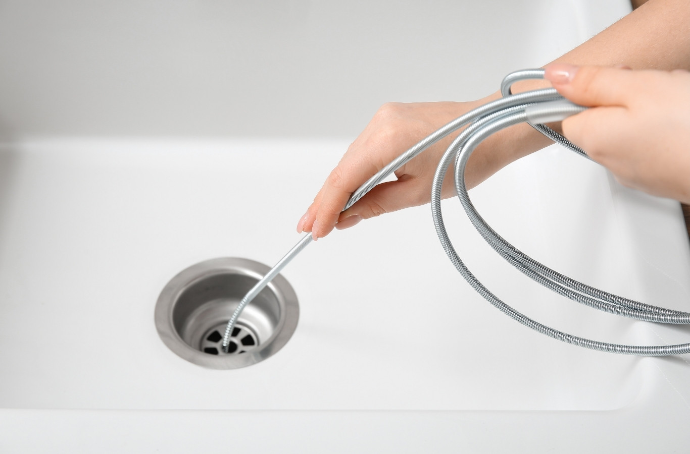 Cable fed into a white sink drain, a clog cleared by Starling Plumbing in Kodak, TN. Drain & Sewer Services Near Me.