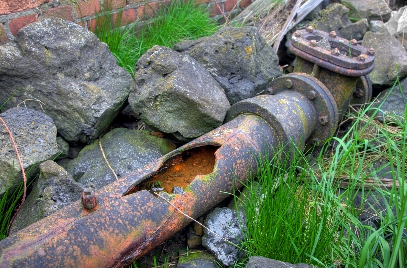 Corroded, broken pipe lying among rocks and grass, the kind of failed line Starling Plumbing replaces in Boyds Creek, TN