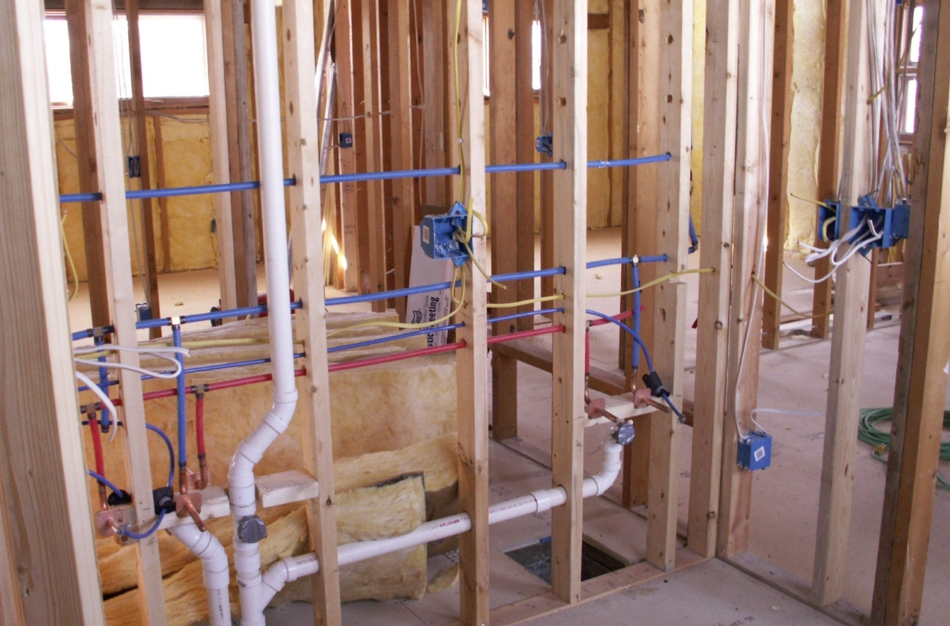 White drain lines and supply pipes in open wall framing, the kind of piping Starling Plumbing works on in Newport, TN