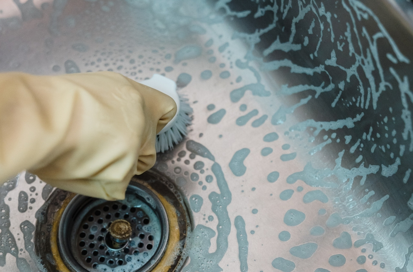 Gloved hand scrubbing a sink strainer, tidy work by Starling Plumbing in Seymour, TN. Drain & Sewer Services Near Me.