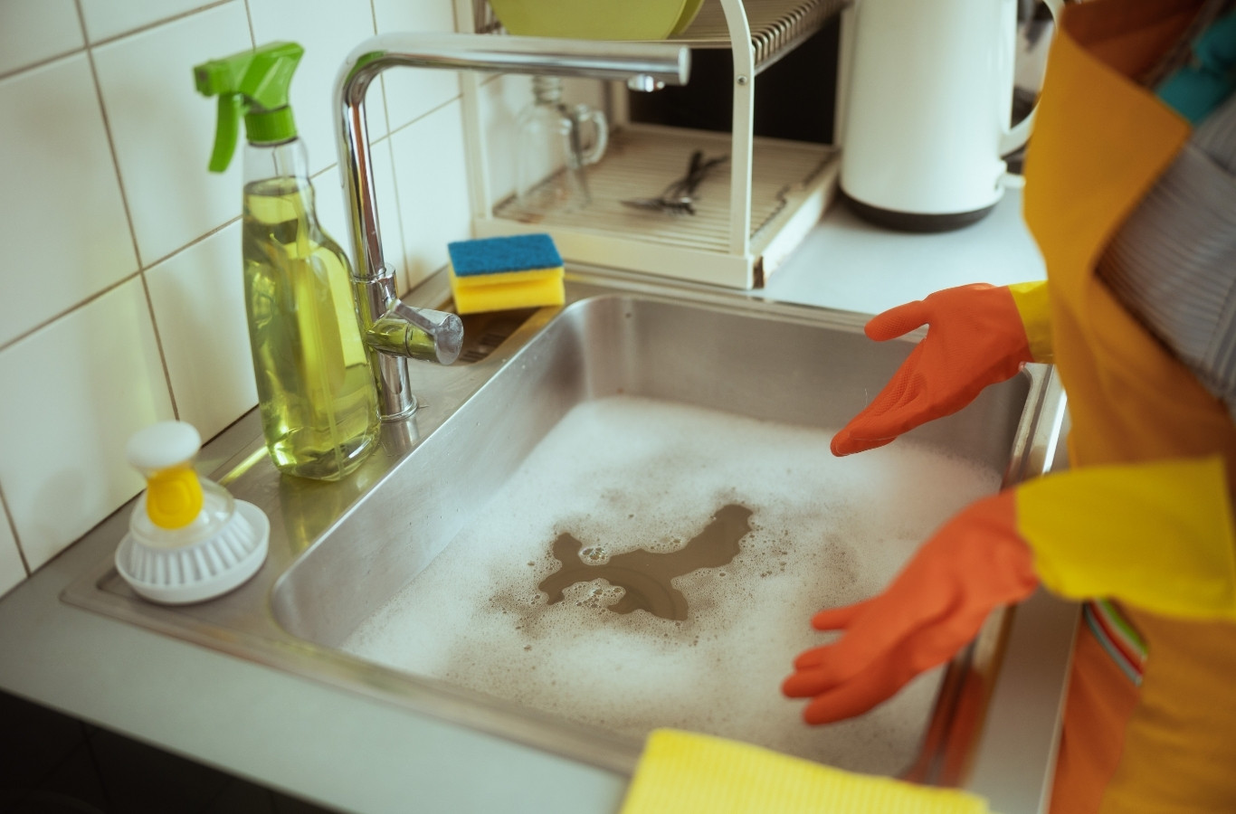 Gloved hands over a kitchen sink full of dirty water, the kind of clog Starling Plumbing clears in Dandridge, TN homes