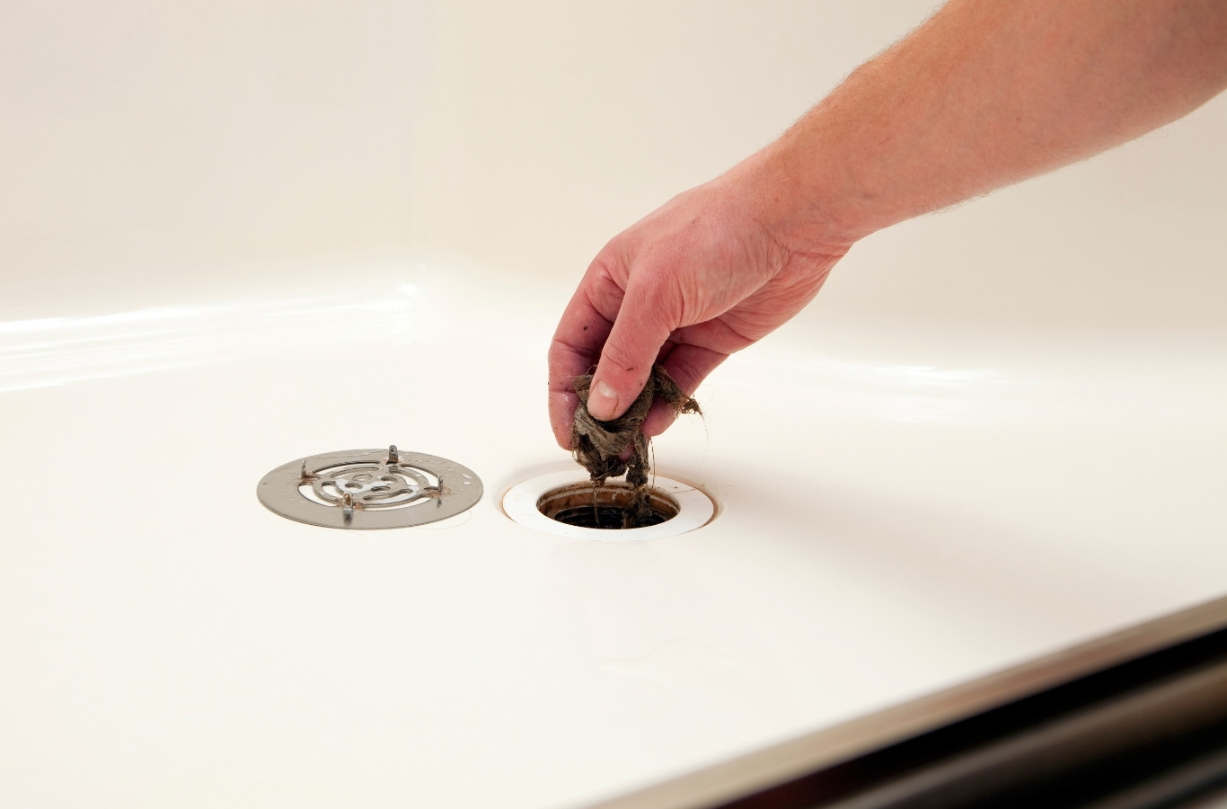 Hand lifting a tub drain stopper clogged with debris, a slow drain Starling Plumbing clears in White Pine, TN homes