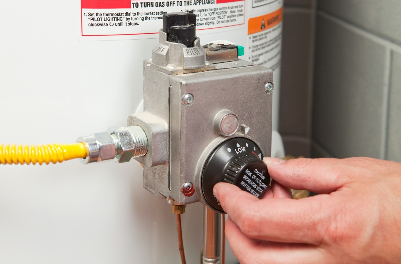 Hand turning the gas control knob on a tank water heater, the kind of check Starling Plumbing makes in Talbott, TN