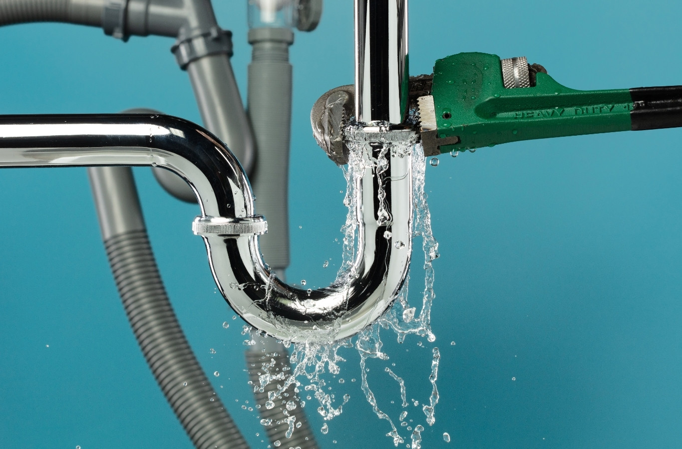 Water leaking from a chrome sink trap beside a pipe wrench, the kind of leak Starling Plumbing repairs in Blaine, TN