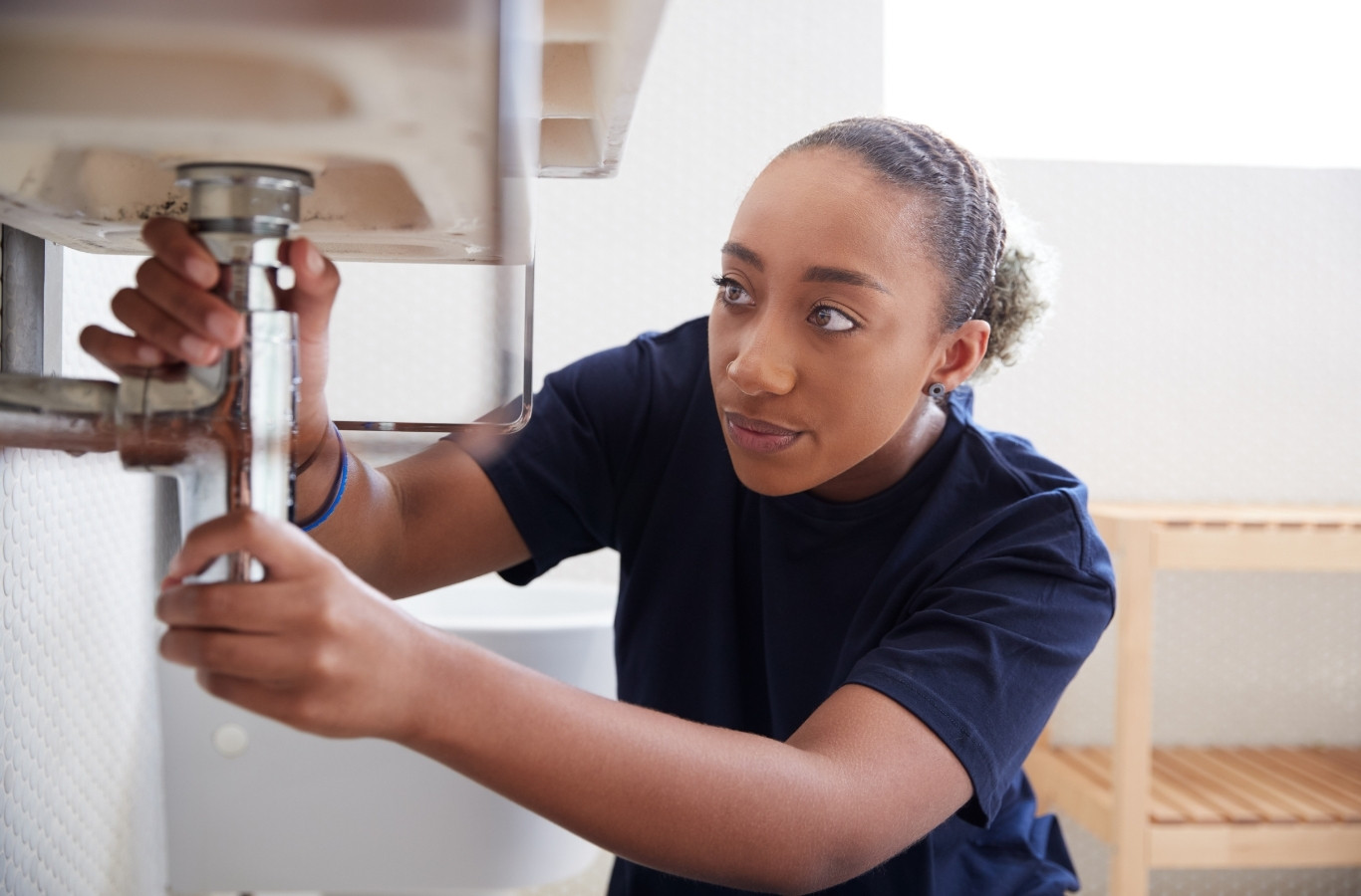 Plumber loosening a sink drain pipe under a basin, the kind of fix Starling Plumbing makes for Russellville, TN homes