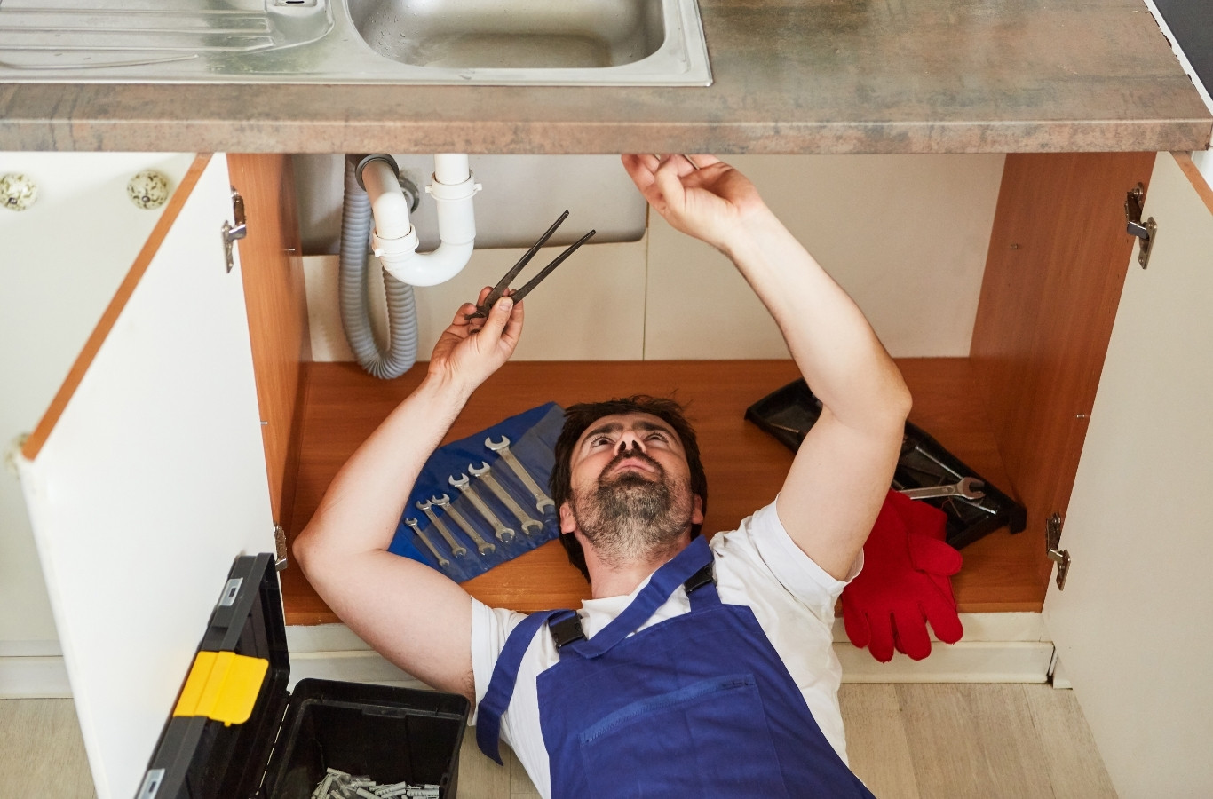 Plumber reaching up under a kitchen sink cabinet, careful repairs by Starling Plumbing in Rutledge, TN. Plumber Near Me.