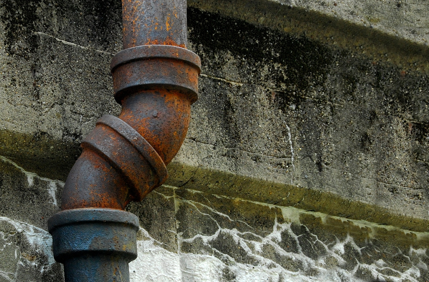 Rusty cast iron drain pipe running down an old wall, the aging piping Starling Plumbing replaces in Rutledge, TN homes