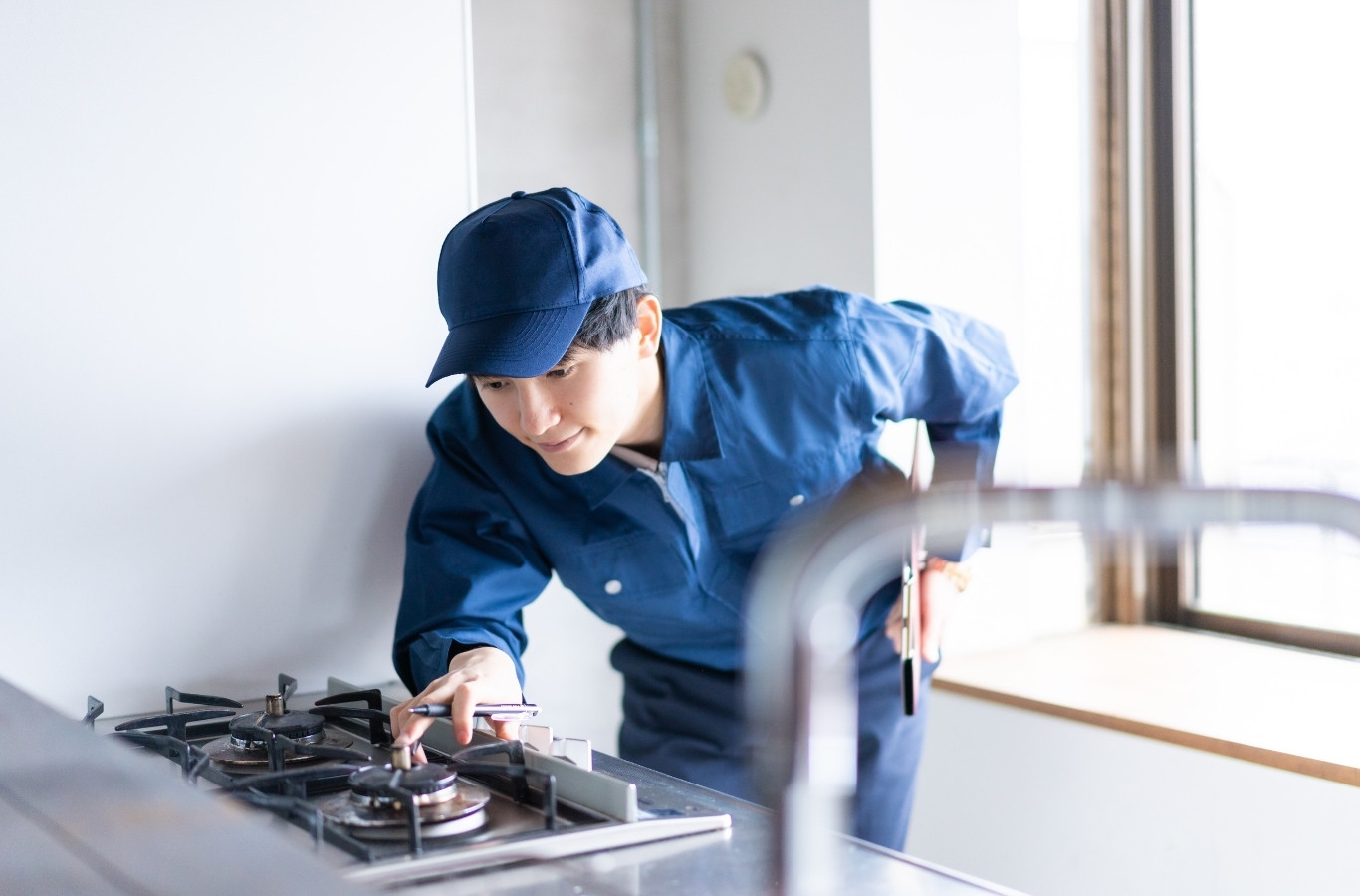 Technician checking the gas connection at a kitchen cooktop, gas work Starling Plumbing does in Sevier County, TN