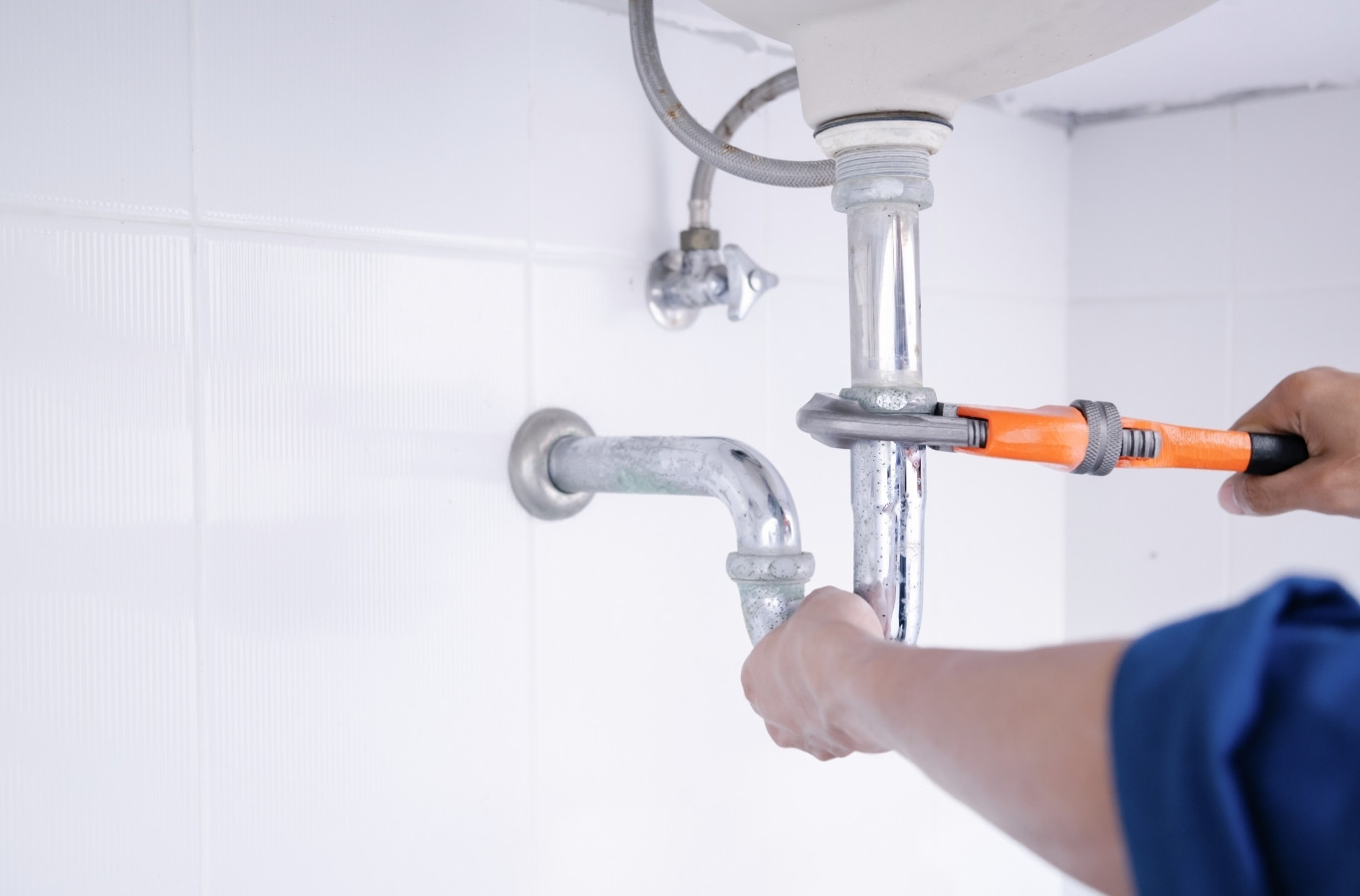 Orange wrench on a chrome pipe under a bathroom sink, the kind of fix Starling Plumbing makes in Bean Station, TN homes