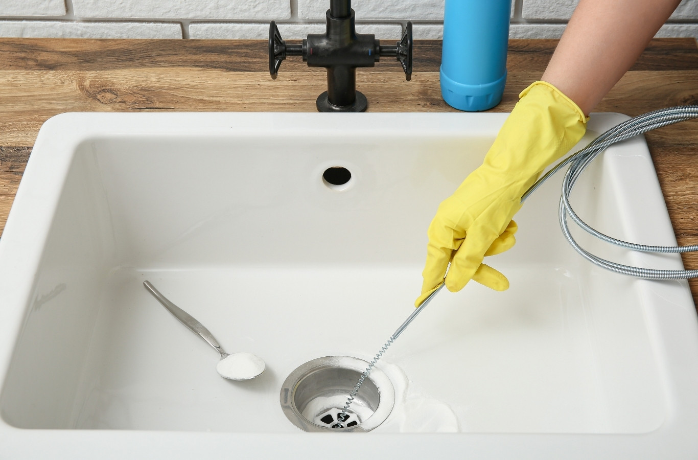 Gloved hand feeding a cable into a clogged sink drain, a drain fix Starling Plumbing offers in White Pine, TN homes